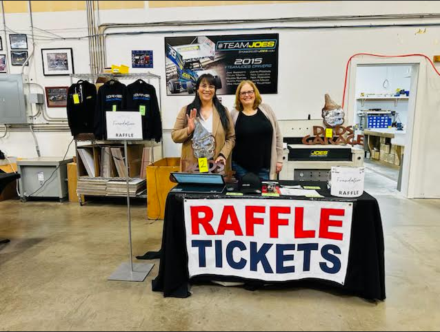Lisa Melcher, left and Lisa Fritch, right stand behind the Sno-Isle Skills Tech Center Foundation raffle tickets table